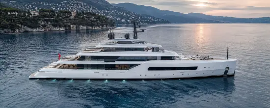 Ultra-realistic aerial view of a white luxury superyacht cruising along a Mediterranean coastline at sunset, with calm blue water, coastal villas and mountains in the background.