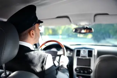 Private chauffeur driving a luxury vehicle, viewed from the rear passenger seat.