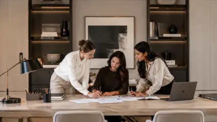 Two assistants and a chief of staff working together in a refined office with soft neutral interiors.